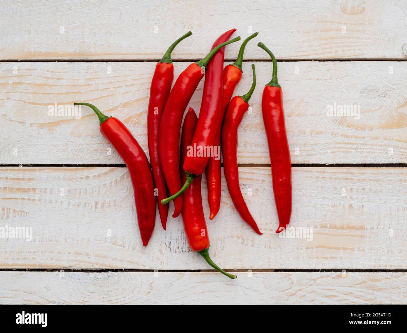 Grundansicht von roten Chilischoten auf einem weißen, rustikalen Hintergrund mit Holztäfelung. Stockfoto