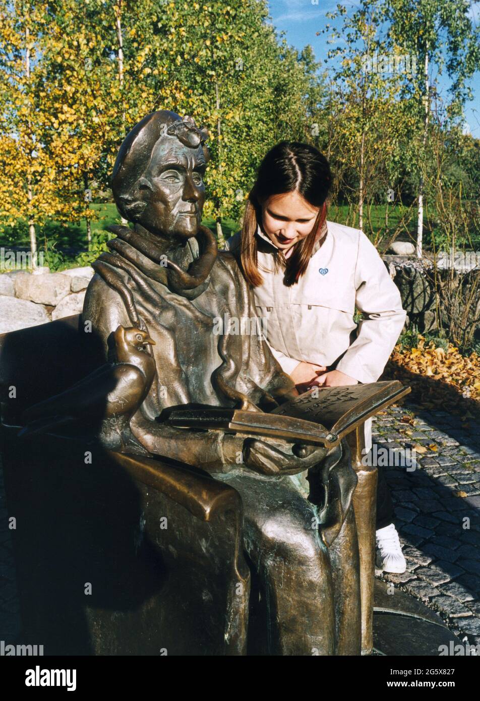 ASTRAD LINDGREN Statue vor den Junibacken der Erkundungs- und Spielplatz für Kinder.Junges Mädchen lehnt sich über die Armlehne und liest im Buch Stockfoto