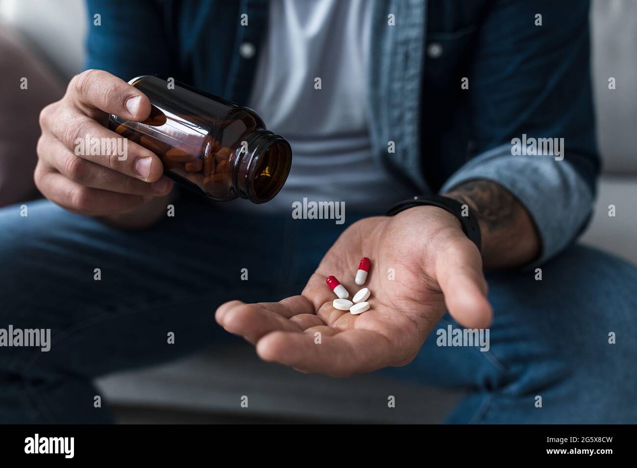 Eine Handvoll weißer Pillen in der Handfläche männlicher Patienten. Gesundheit, Behandlung, Medikamente und Depressionen, Schmerzen und Selbstmord Stockfoto
