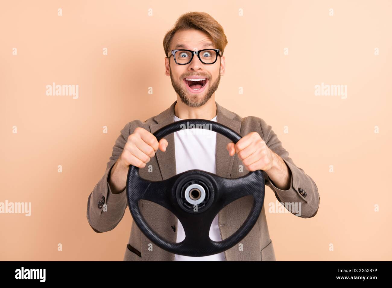 Foto von glücklich aufgeregt gute Laune verrückt Geschäftsmann Reiten Auto halten Lenkrad isoliert auf beige Farbe Hintergrund Stockfoto