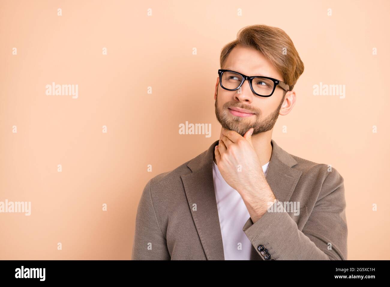 Foto von optimistisch schöne blonde Haare Mann suchen leeren Raum tragen Brille  graue Jacke auf beige Farbe Hintergrund isoliert Stockfotografie - Alamy