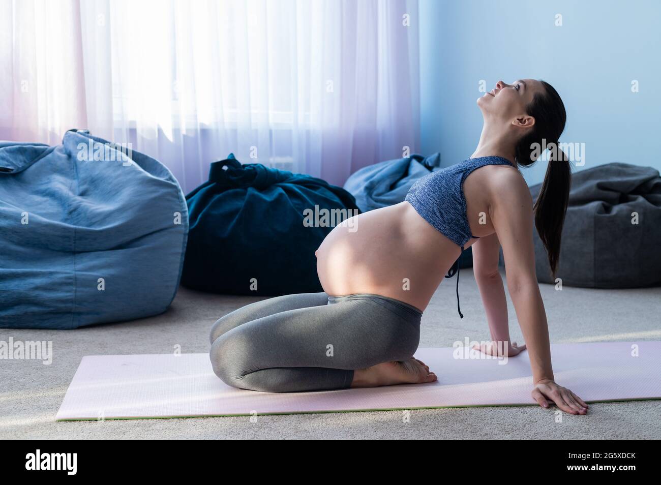 Schöne junge, schwanger Frau ist in Pilates verwickelt. Die werdende Mutter spielt Sport, während sie auf die Geburt eines Kindes wartet. Stockfoto