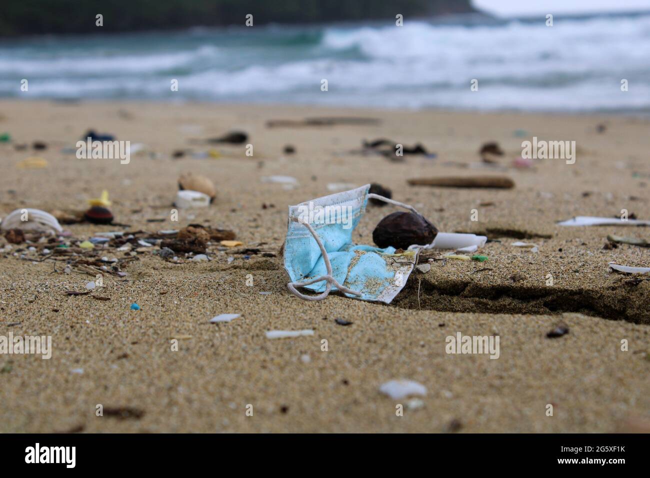 Eine Schutzmaske gegen Covid 19, die Teil des Mülls am Strand ist. Stockfoto