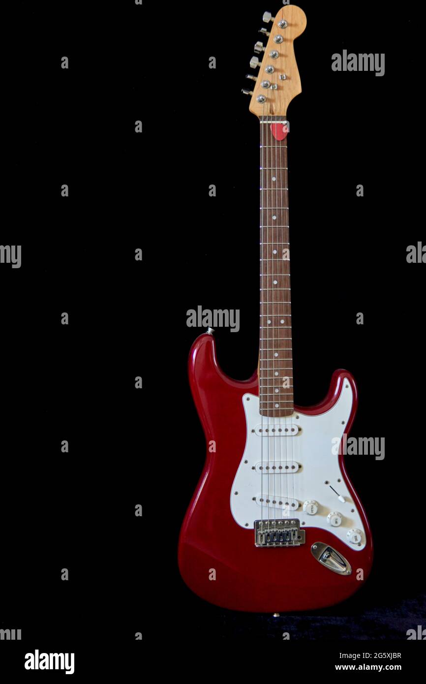 Elektrische Gitarre isoliert mit rotem Plektrum auf schwarzem Hintergrund. Vertikal und Kopierraum Stockfoto