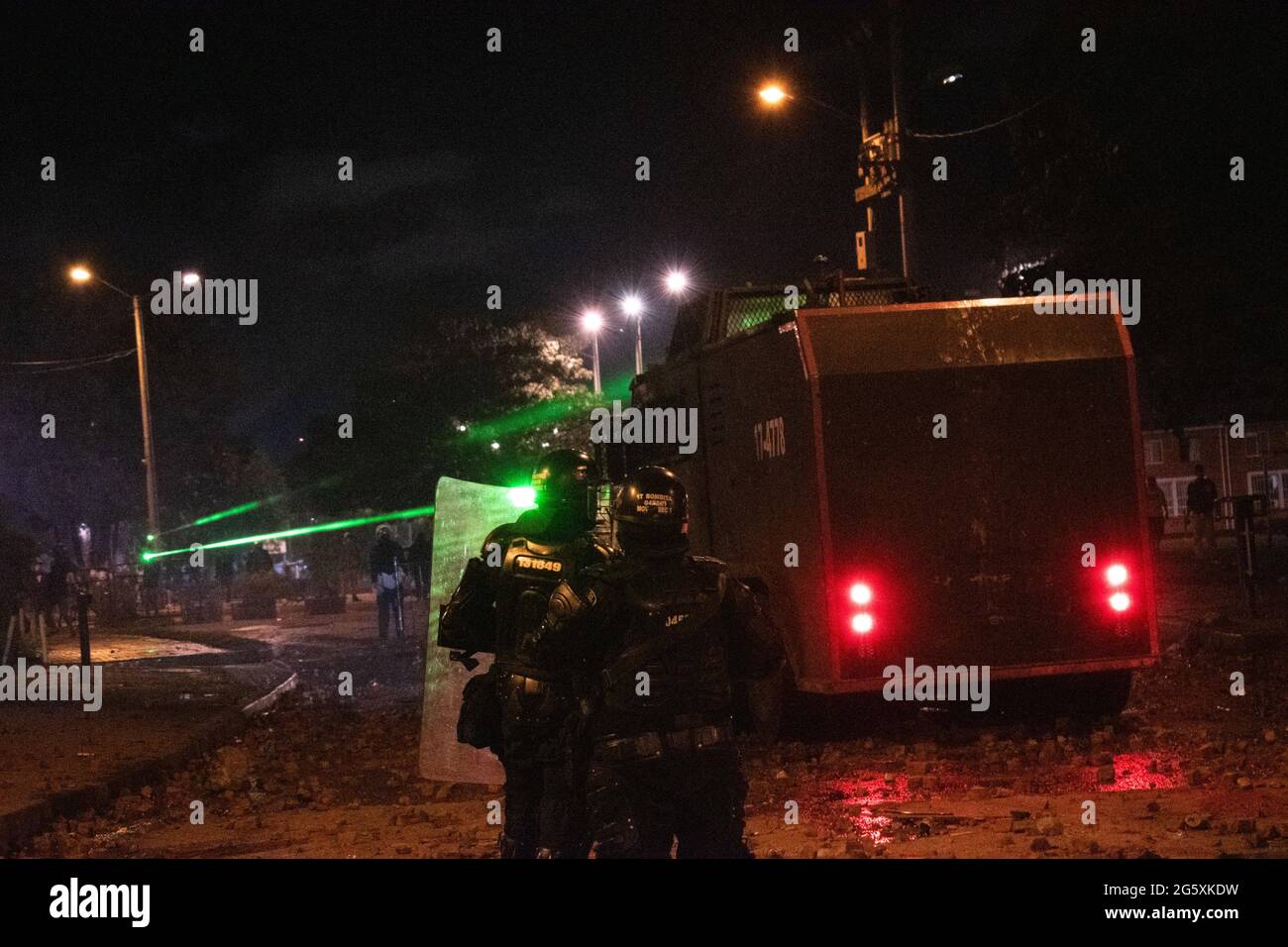 Bogota, Kolumbien. Juni 2021. Kolumbianische Polizeibeamte decken sich hinter einem gepanzerten Lastwagen ab, als die Einwohner von Fontanar - Suba in Bogota, Kolumbien, protestierten und gegen die kolumbianische Bereitschaftspolizei (Escuadron Movil Antidisturbios ESMAD) gegen den Besuch des kolumbianischen Präsidenten Ivan Duque Marquez in einem Park, in dem Bogotas U-Bahn-System gebaut werden soll, einschlugen. Inmitten von zwei Monaten regierungsfeindlicher Proteste gegen den Präsidenten Ivan Duque Marquez, Ungleichheiten und Polizeiunruhen während der Proteste am 29. Juni 2021. Kredit: Long Visual Press/Alamy Live Nachrichten Stockfoto