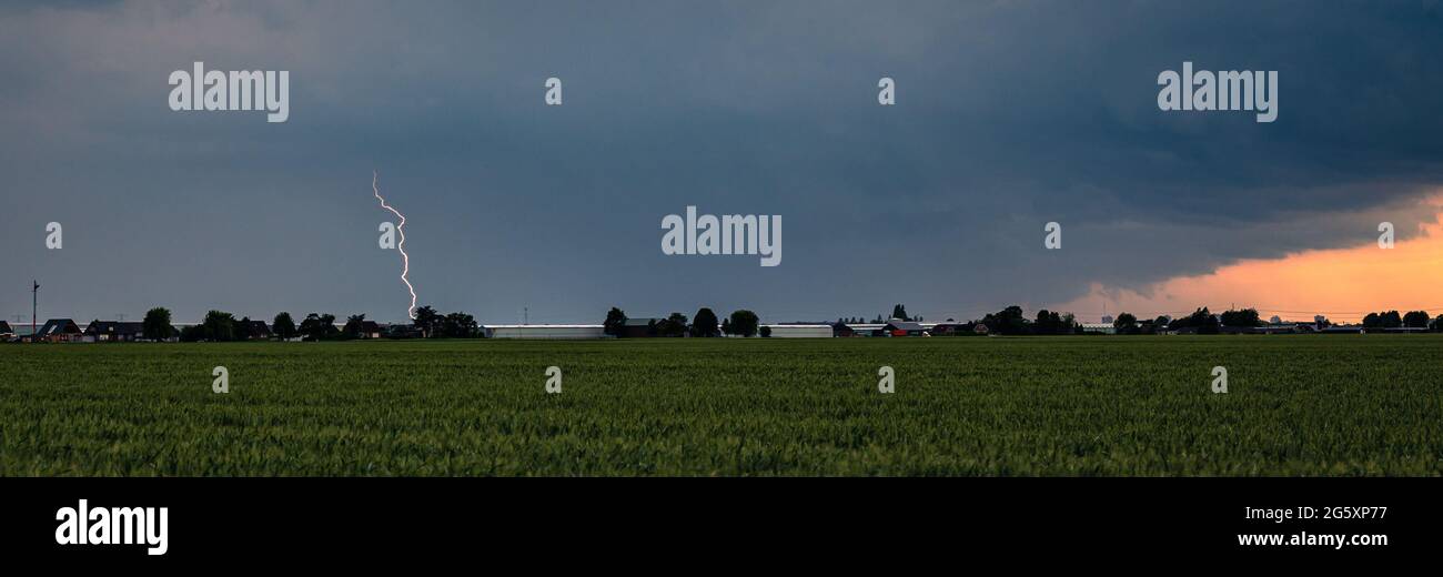 Panorama einer Sturmwolke mit Blitzeinschlag bei Sonnenuntergang Stockfoto