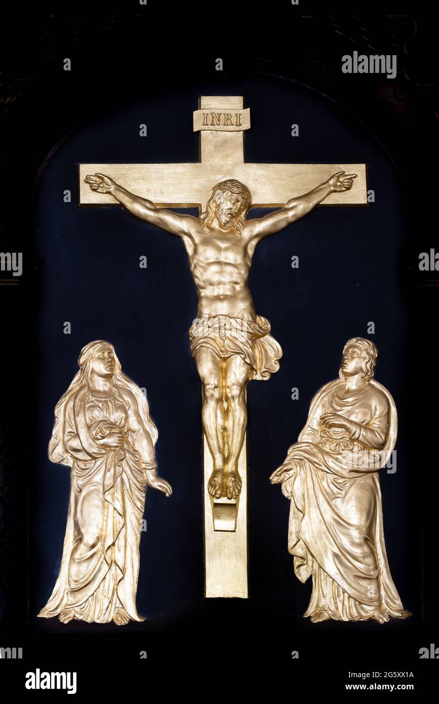 Ein goldenes Relievo der Kreuzigung mit der Jungfrau Maria und dem heiligen Johannes auf schwarzem Hintergrund, Skibby, Dänemark, 28. Juni 2021 Stockfoto