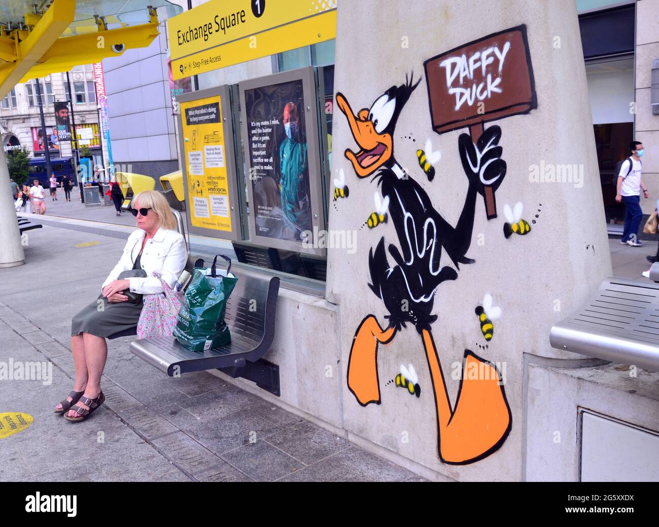 Eine Frau sitzt neben einem Bild der Zeichentrickfigur Daffy Duck, Teil eines Looney Tunes-Kunstpfades, der in Manchester, England, eröffnet wurde. Stockfoto