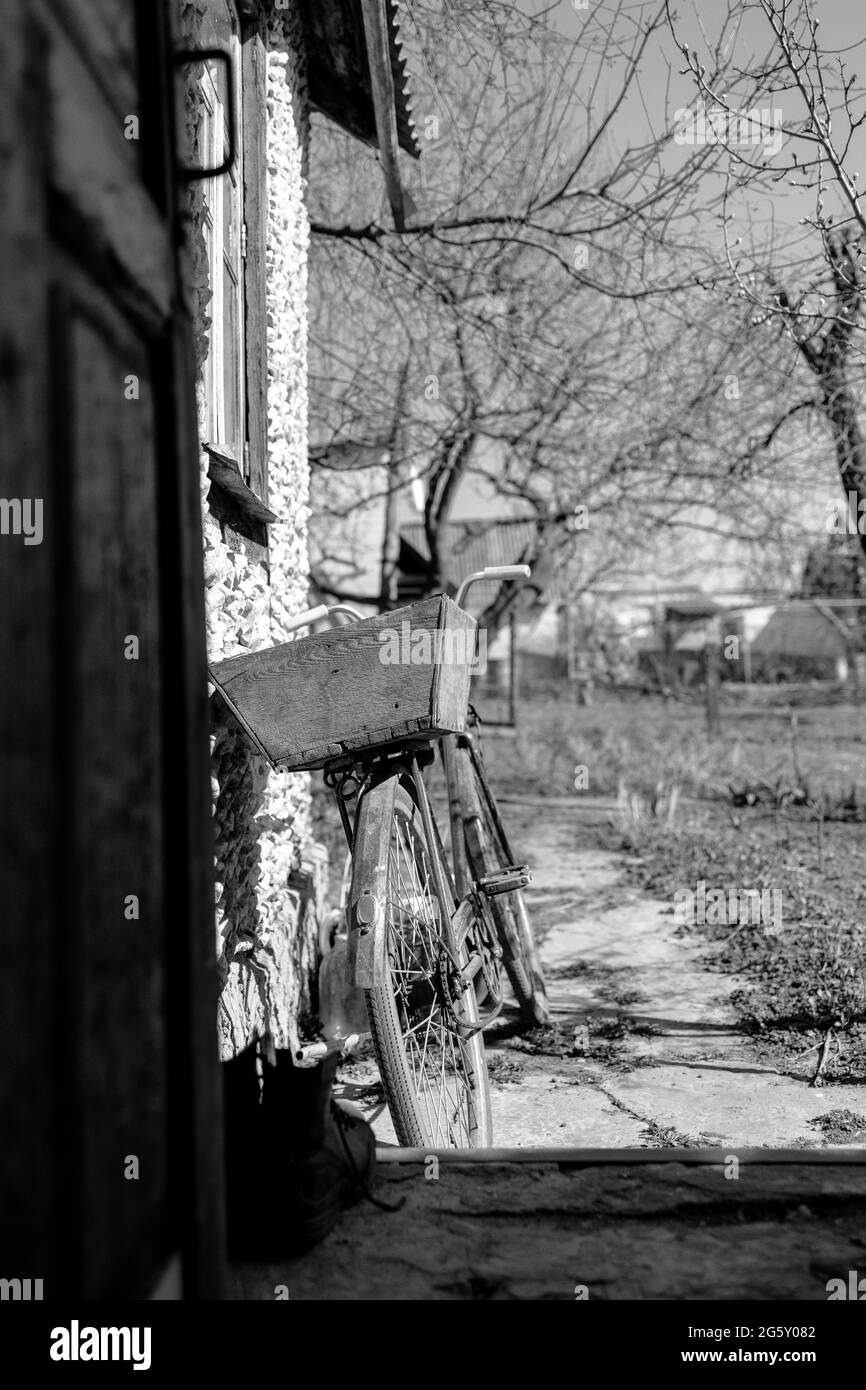 Altes Fahrrad steht in der Nähe der Wand, Rückansicht. Schwarzweiß-Foto. Stockfoto