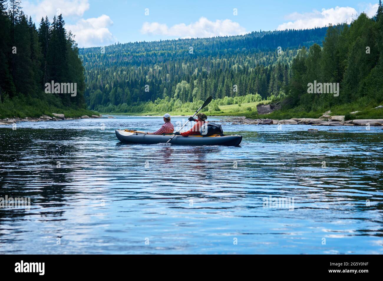 Ein paar Touristen in einem zweisitzigen Kajak, das den Fluss hinunter in die Berge rast Stockfoto