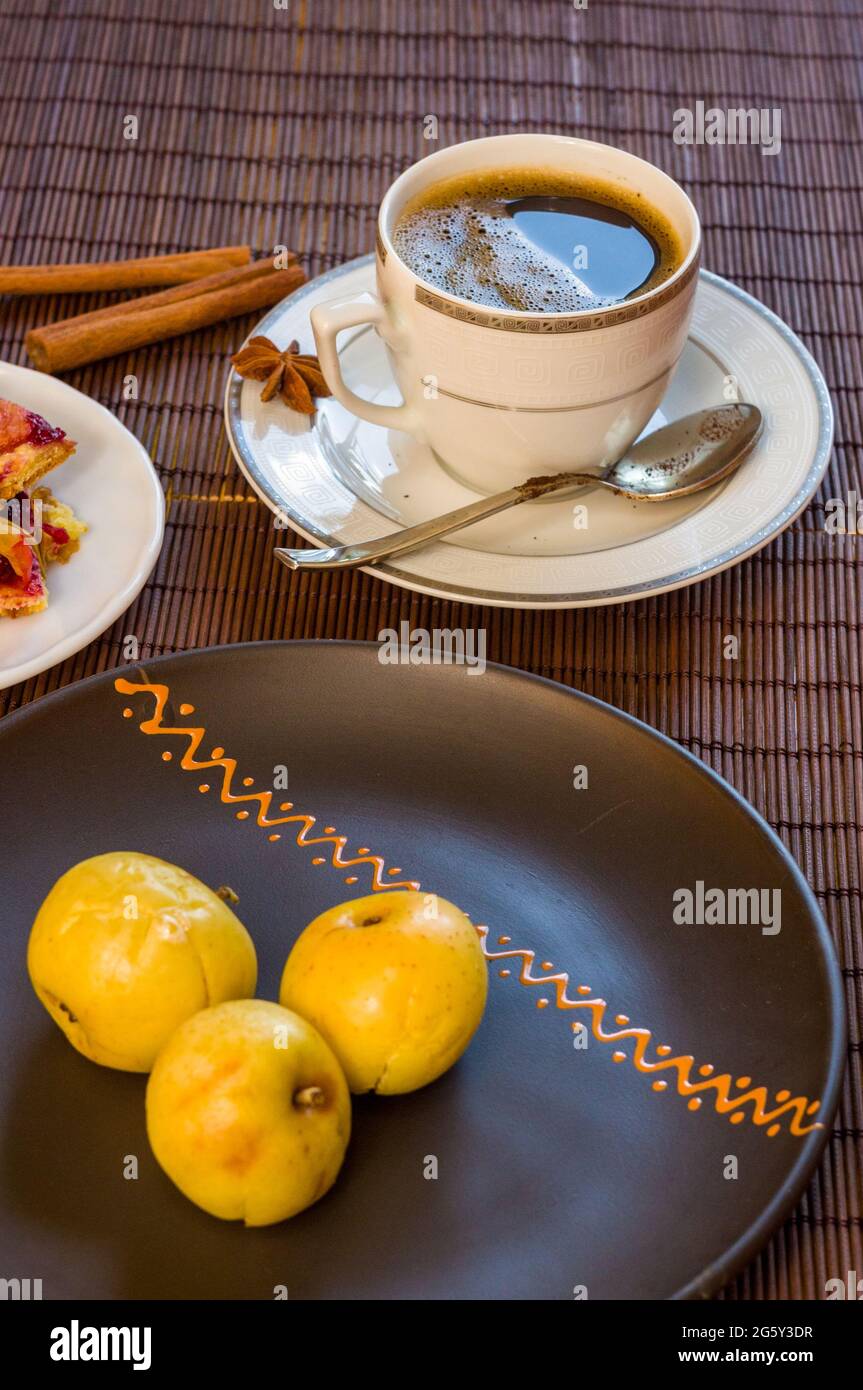 Stillleben - eine Tasse schwarzen Kaffee, hausgemachte Kekse mit Obst, gebackene Äpfel auf einer Bambusmatte Stockfoto