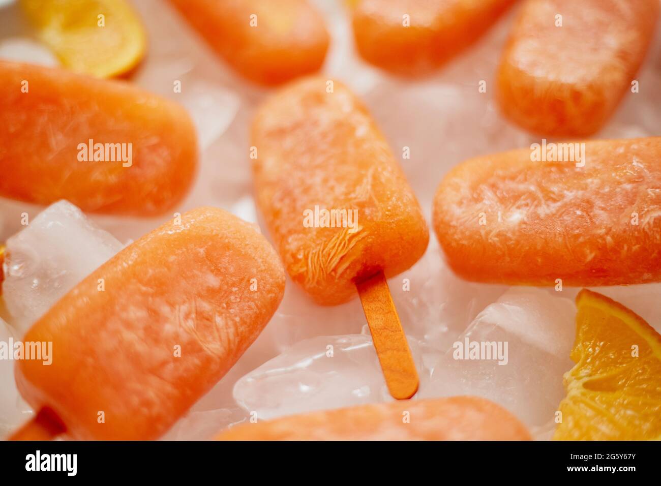 Hausgemachte gefrorene Eis-Eiszapfen mit oragnic frischen Orangen mit Eiswürfeln auf Marmortisch platziert gemacht Stockfoto