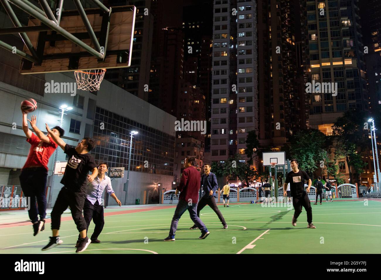 In Hongkong wird nachts auf einem Tennisplatz im Stadtzentrum Basketball gespielt Stockfoto