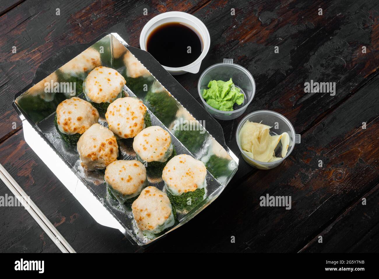 Sushi-Rollen im Takeaway-Container-Set, auf altem dunklen Holztischhintergrund, mit Copyspace und Platz für Text Stockfoto