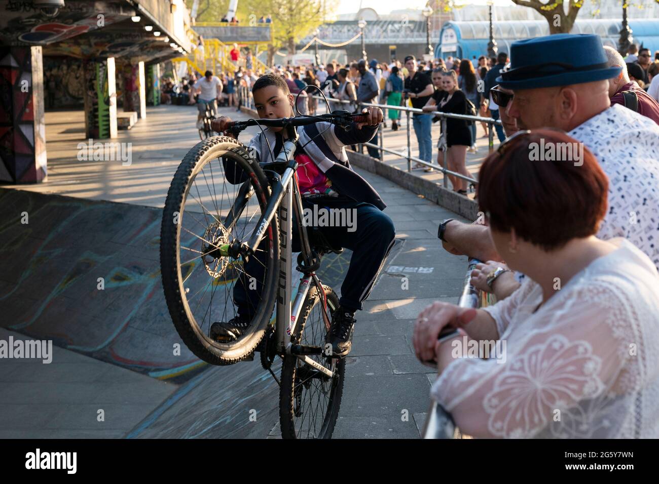 Jungs machen Stunts auf Fahrrädern, während Touristen im Southbank Skate Space in London, Großbritannien, zusehen Stockfoto