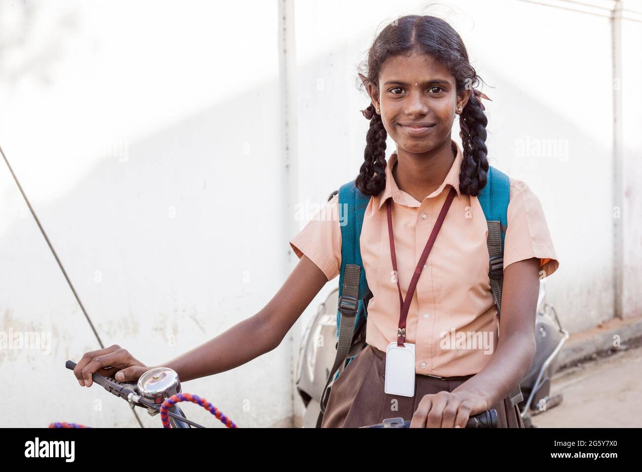 Hübsches indisches Schulmädchen in Uniform mit Rucksack sitzt auf dem Fahrrad und lächelt fröhlich für Foto, Puducherry, Tamil Nadu, Indien Stockfoto