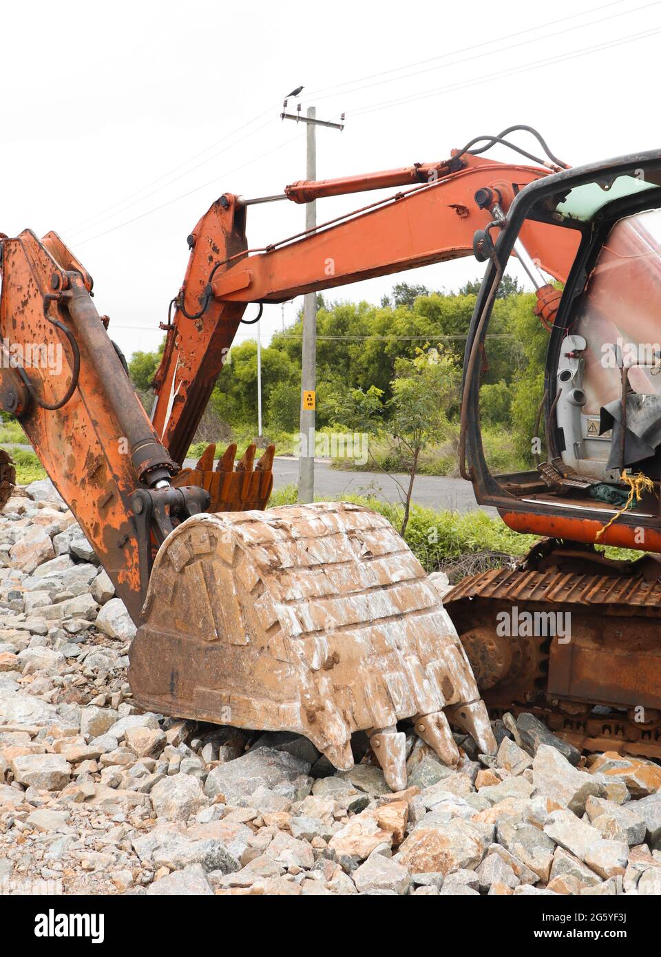 Orangefarbene, rostige, abgenutzte Bulldozer-Bagger vor Ort, die am Nachmittag in einem kargen Land Bauarbeiten durchmachten Stockfoto