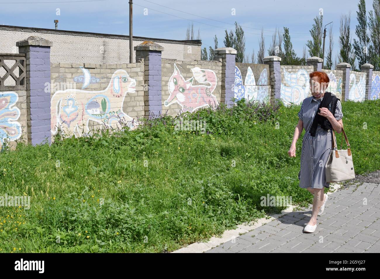 Ein Bewohner von Kramatorsk geht an den Straßenkunstgemälden im zentralen Teil der Stadt vorbei. Die Straßenkunstkultur der Ukraine ist mutig und erfrischend und zeigt den kraftvollen Geist der Jugend des Landes. Künstler verbinden sowjetische Einflüsse nahtlos mit bekannten Prüfsteinen wie der amerikanischen Hip-Hop-Kultur und dem Abstrakten Expressionismus, eine Art Verschmelzung mit manchmal nationalen Kunsttraditionen. Straßenkunstmaler in der modernen Ukraine reisen oft von West- in den Ostteil des Landes, um die Straßen der Stadt bunter und neugieriger zu machen. Stockfoto