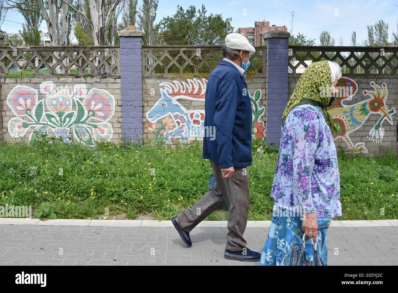 Ältere Bewohner von Kramatorsk gehen an den Straßenmalereien im zentralen Teil der Stadt vorbei. Die Straßenkunstkultur der Ukraine ist mutig und erfrischend und zeigt den kraftvollen Geist der Jugend des Landes. Künstler verbinden sowjetische Einflüsse nahtlos mit bekannten Prüfsteinen wie der amerikanischen Hip-Hop-Kultur und dem Abstrakten Expressionismus, eine Art Verschmelzung mit manchmal nationalen Kunsttraditionen. Straßenkunstmaler in der modernen Ukraine reisen oft von West- in den Ostteil des Landes, um die Straßen der Stadt bunter und neugieriger zu machen. Stockfoto
