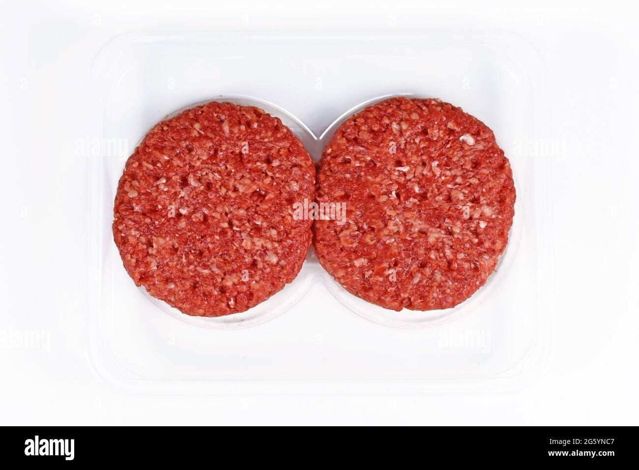 Zwei rohe, runde Burger-Patties in einer Packung auf weißem Hintergrund Stockfoto