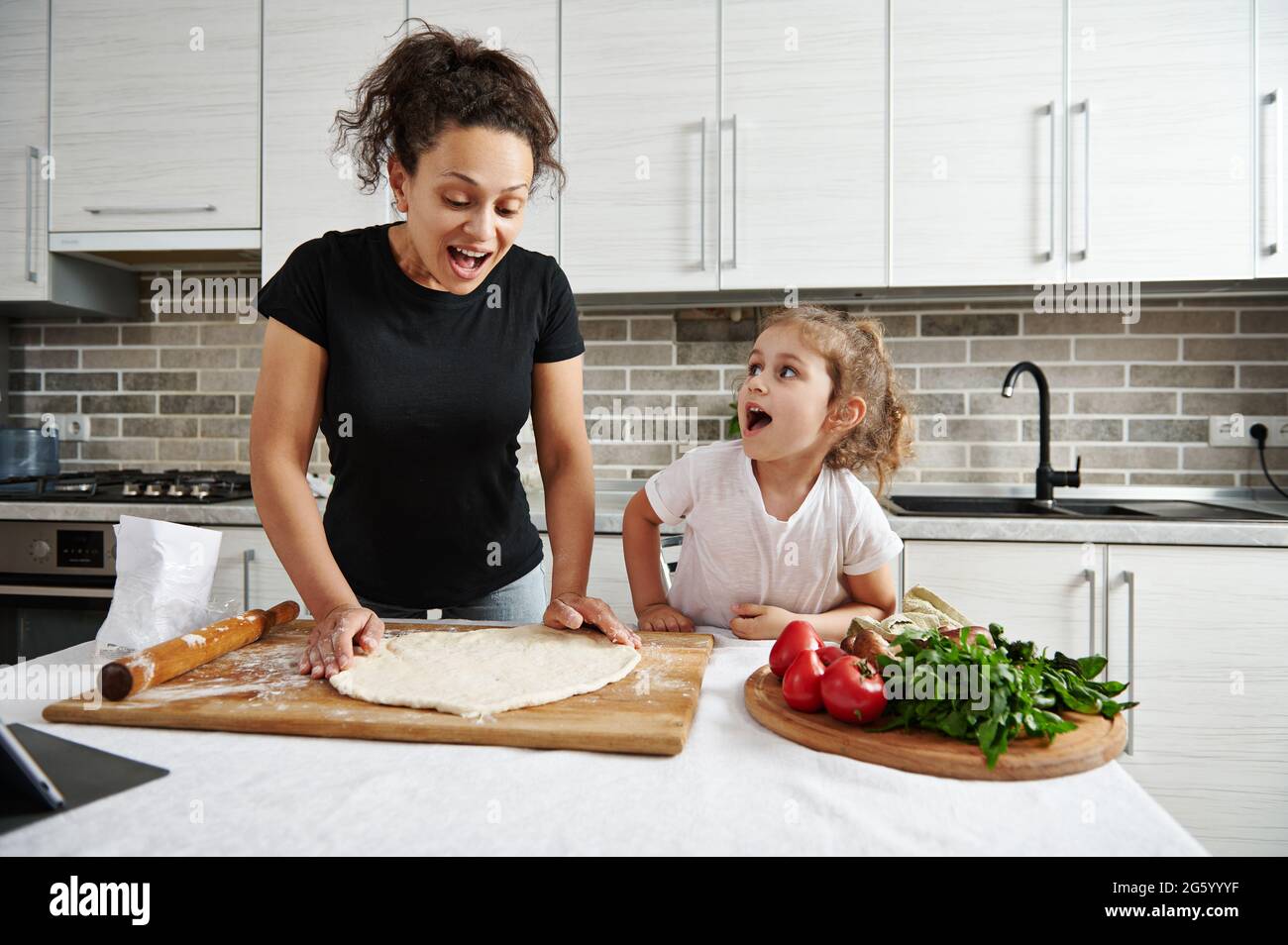 Familienverbringe Zeit Konzept. Kindern beim Kochen beibringen. Glückliche Mutter und Tochter bilden eine runde Form von Pizzateig, kochen zusammen zu Hause. Stockfoto