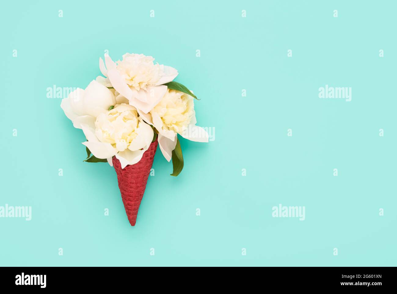 Weiße Pfingstrosen-Blüten in einem roten Waffel-Eiscreme-Kegel auf einem sonnengebackenen Minze-Hintergrund. Muttertag, Valentinstag, Bachelorette, Sommerkonzept. Stockfoto