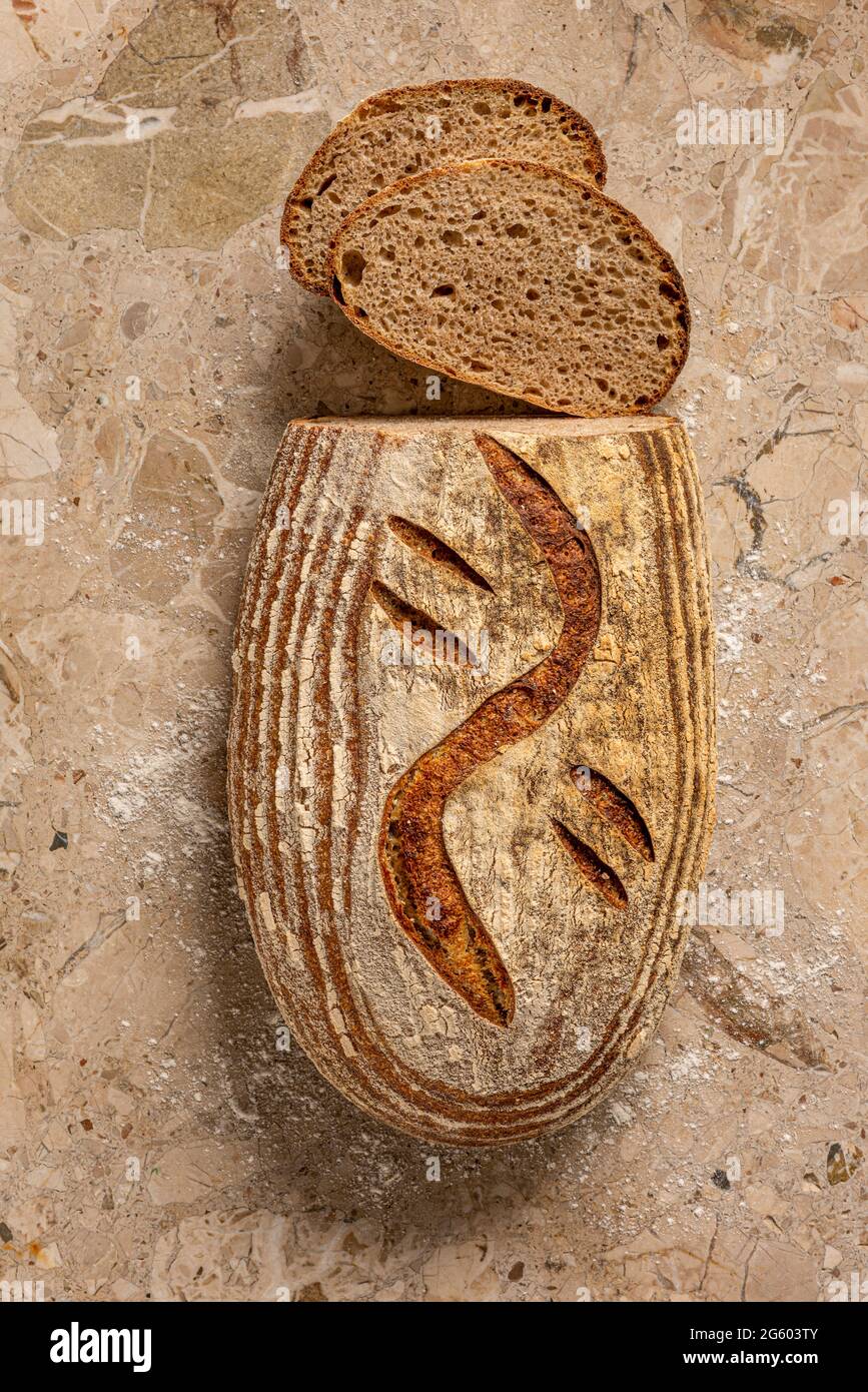 Flache Ansicht von handgefertigtem Sauerteig-Brot auf einer Arbeitsfläche aus hellbraunem Marmor. Frisch gebacken und in Scheiben geschnitten. Stockfoto