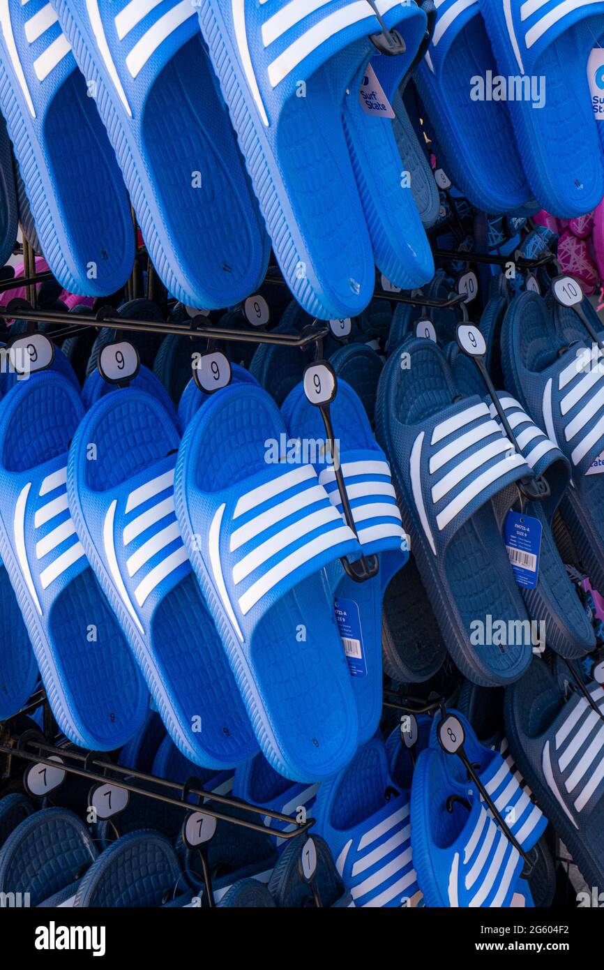 Eine Anzeige von blauen und weißen Sliders Sandalen zum Verkauf. Stockfoto