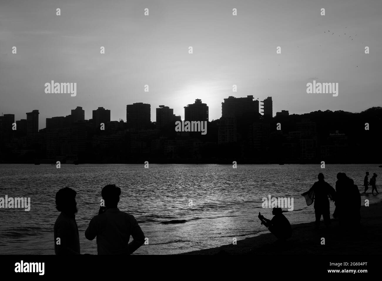 Silhouetten von Menschen und Wolkenkratzern bei Sonnenuntergang am Marine Drive Beach in Mumbai Maharashtra India am 2. April 2021 Stockfoto