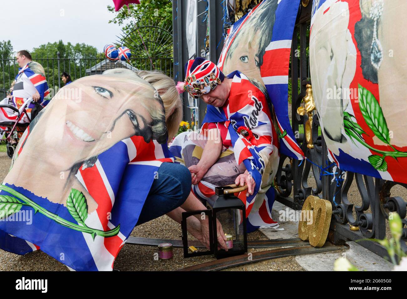 Kensington Palace, London, 1. Juli 2021. Königliche Fans, Maria Scott und John Loughrey, zünden eine Erinnerungskerze vor den Toren des Kensington Palace an, um an den 60. Geburtstag von Prinzessin Diana zu erinnern. Prince's William und Harry werden heute Nachmittag eine Statue zu ihren Ehren im versunkenen Garten enthüllen Credit: amanda Rose/Alamy Live News Stockfoto