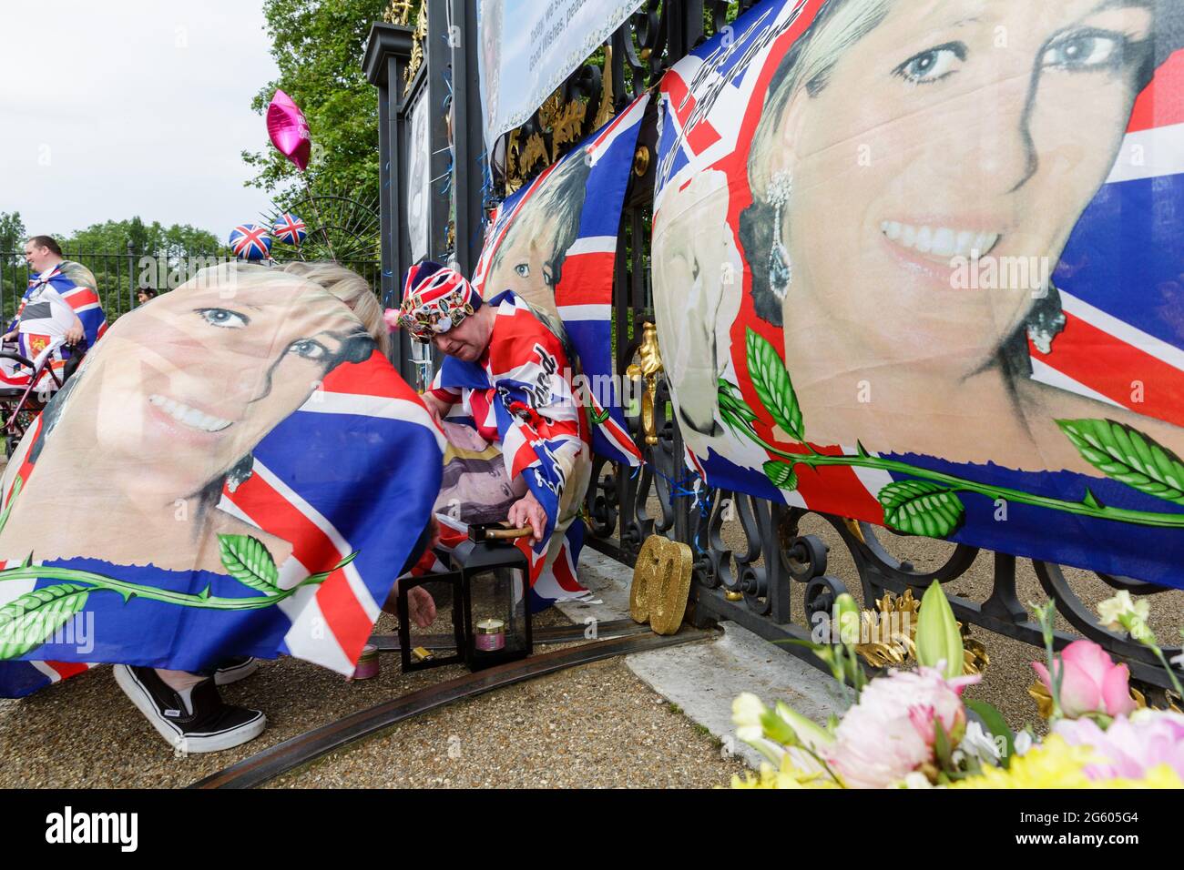 Kensington Palace, London, 1. Juli 2021. Königliche Fans, Maria Scott und John Loughrey, zünden eine Erinnerungskerze vor den Toren des Kensington Palace an, um an den 60. Geburtstag von Prinzessin Diana zu erinnern. Prince's William und Harry werden heute Nachmittag eine Statue zu ihren Ehren im versunkenen Garten enthüllen Credit: amanda Rose/Alamy Live News Stockfoto