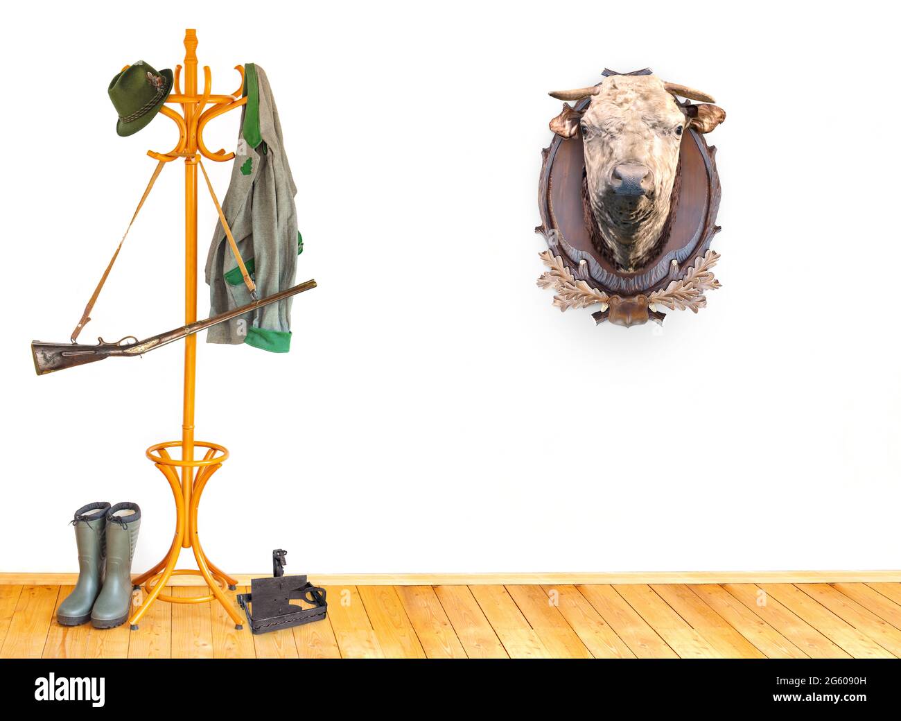 Die Ausrüstung des Jägers in einem Raum mit dem Kopf der Kuh als Trophäe auf einer weißen Wand. Stockfoto