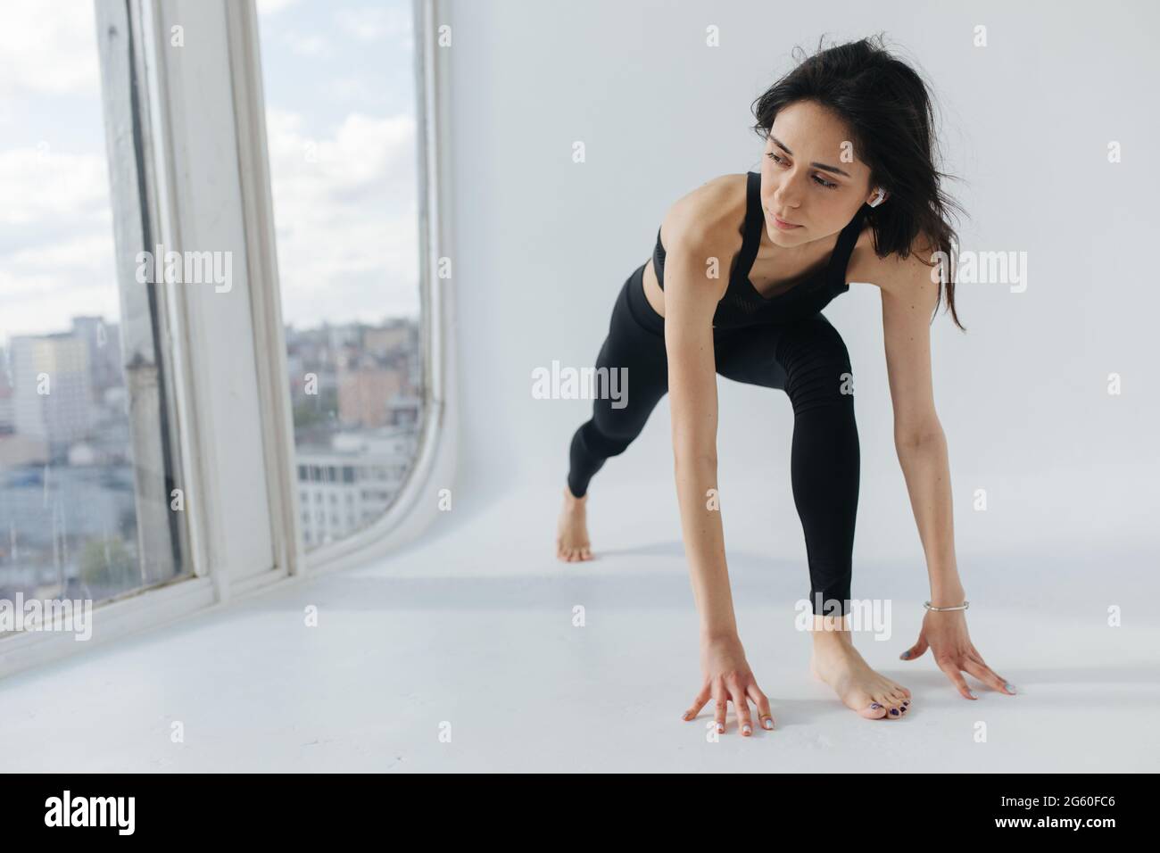 Junge armenische Frau in schwarzer Sportkleidung, die Yoga in Ausfallhaltung praktiziert Stockfoto