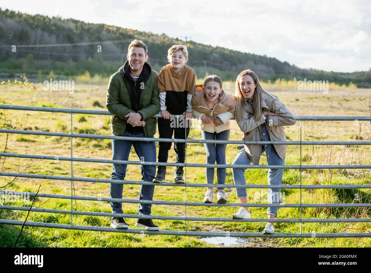 Eine Frontansicht einer kaukasischen Mutter und eines Vaters mit ihrem Sohn und ihrer Tochter, die alle lächeln und auf die Kamera schauen, während sie eine legere Cl tragen Stockfoto