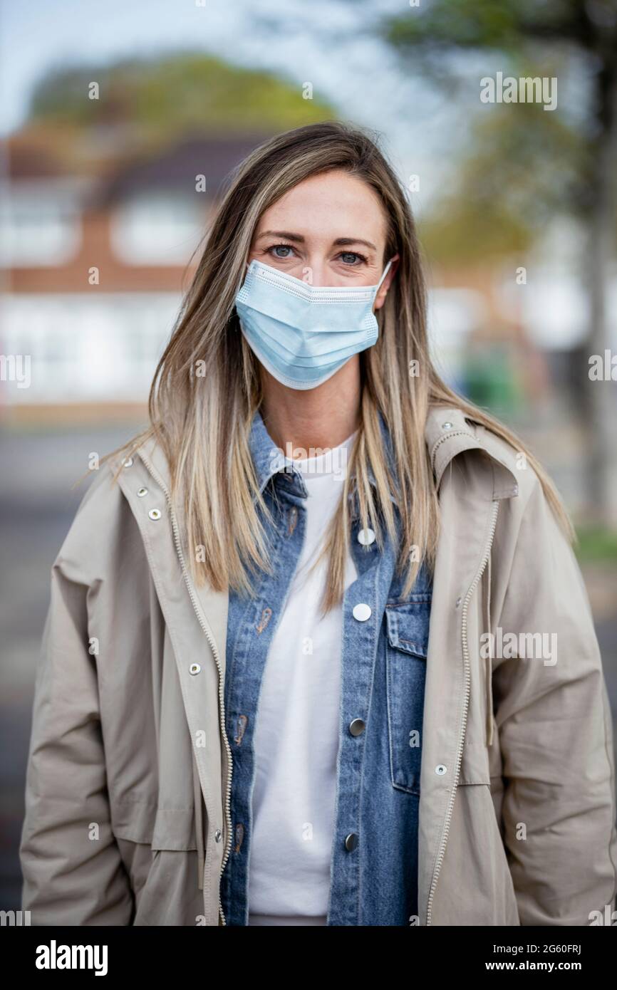 Eine Frontansicht-Portraitaufnahme einer kaukasischen Frau mittleren Erwachsenen in legerer Kleidung, sie lächelt und schaut auf die Kamera. Sie trägt auch ein Prot Stockfoto