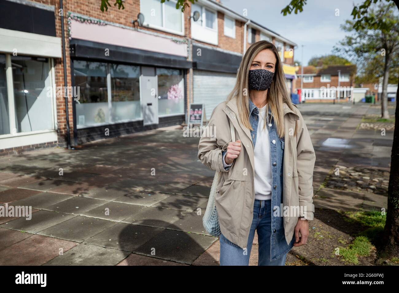 Eine Frontansicht-Portraitaufnahme einer kaukasischen Frau mit mittlerem Erwachsenen in legerer Kleidung, sie lächelt und blickt auf die Kamera. Sie trägt auch Stockfoto