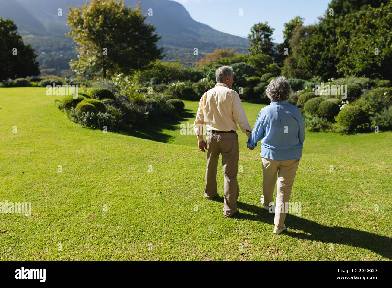 Älteres kaukasisches Paar, das im sonnigen Garten zusammenläuft Stockfoto