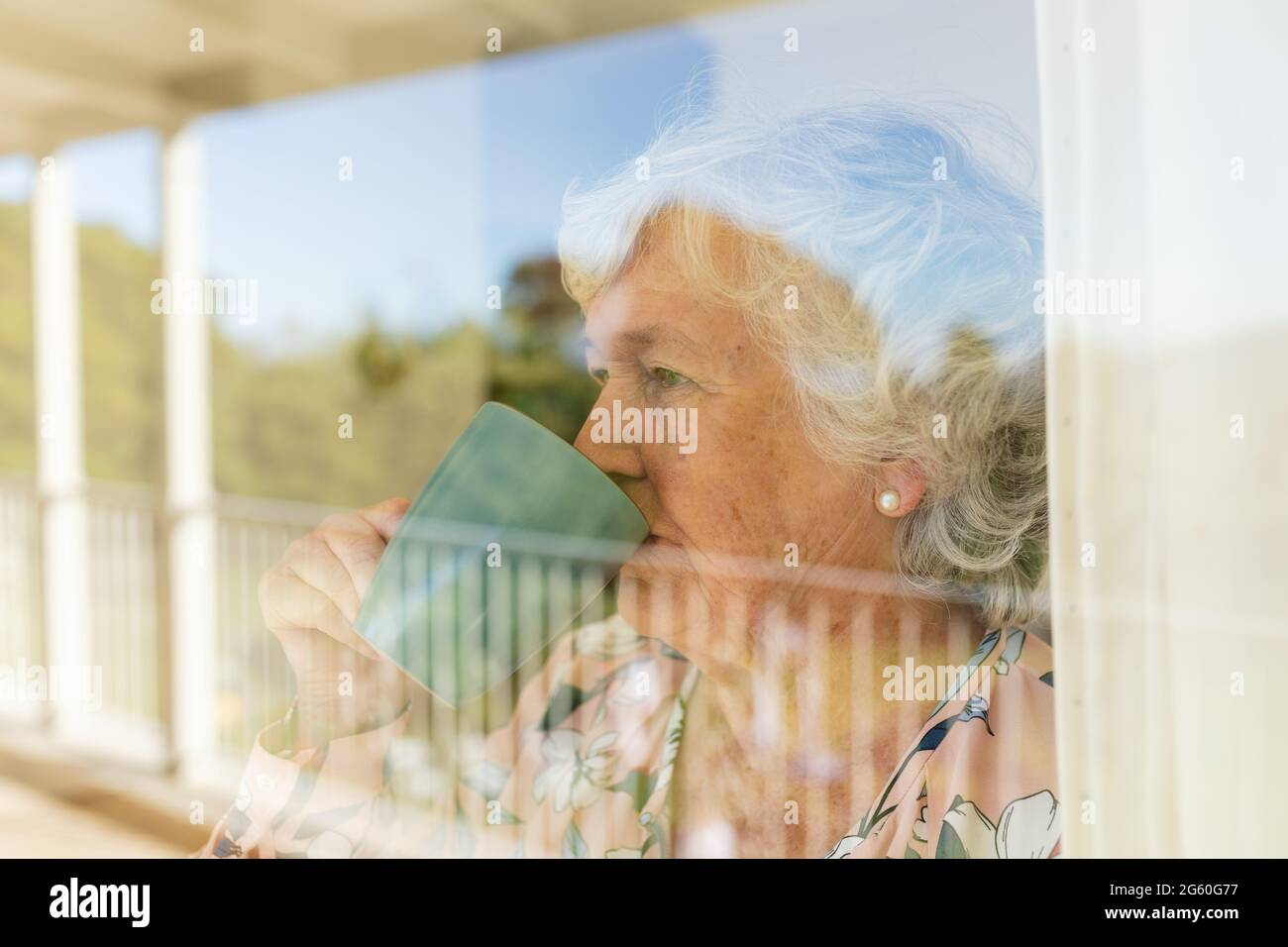 Ältere kaukasische Frau, die durch das Fenster schaute und
