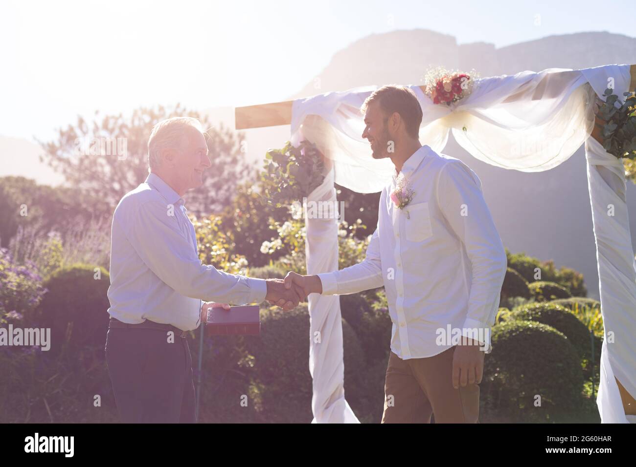 Kaukasischer Bräutigam heiratet und schüttelt sich die Hände mit dem Hochzeitsoffizier Stockfoto