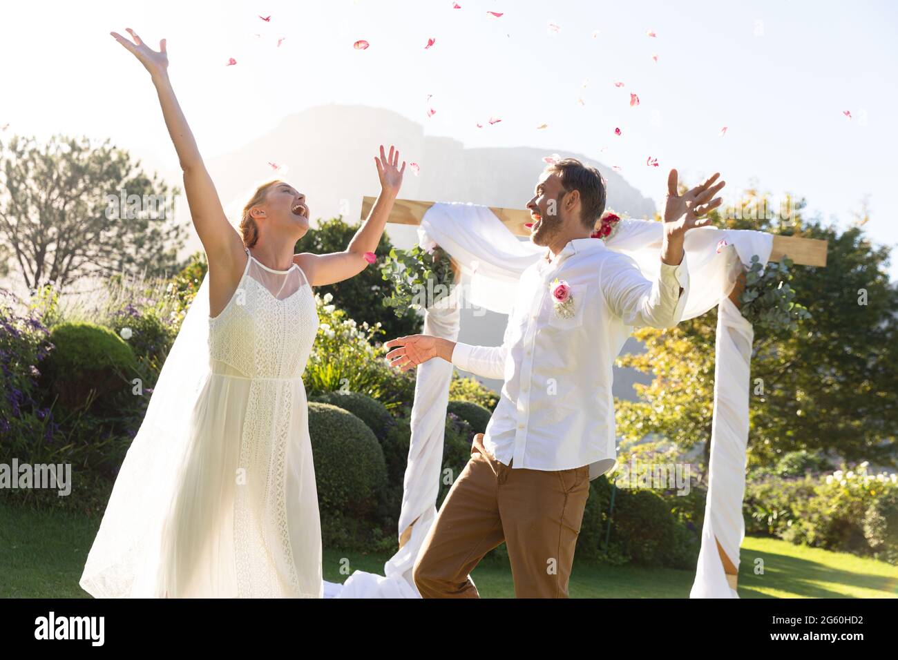 Glückliche kaukasische Braut und Bräutigam heiraten und heben die Hände Stockfoto