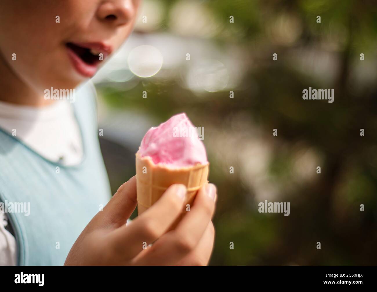Rosa Eiscreme in einem Waffelbecher in Kinderhänden. Stockfoto Rosa Eiscreme in einem Waffelbecher in Kinderhänden. Stockfoto