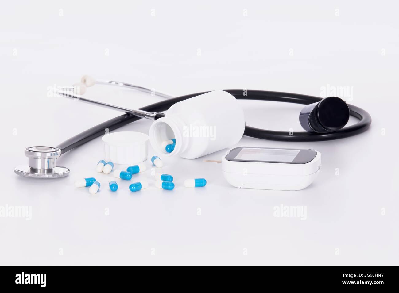 Nahaufnahme von Stethoskop, Blutzuckermessgerät und verschütteten Kapseln:Diabetes- und Gesundheitskonzept. Stockfoto