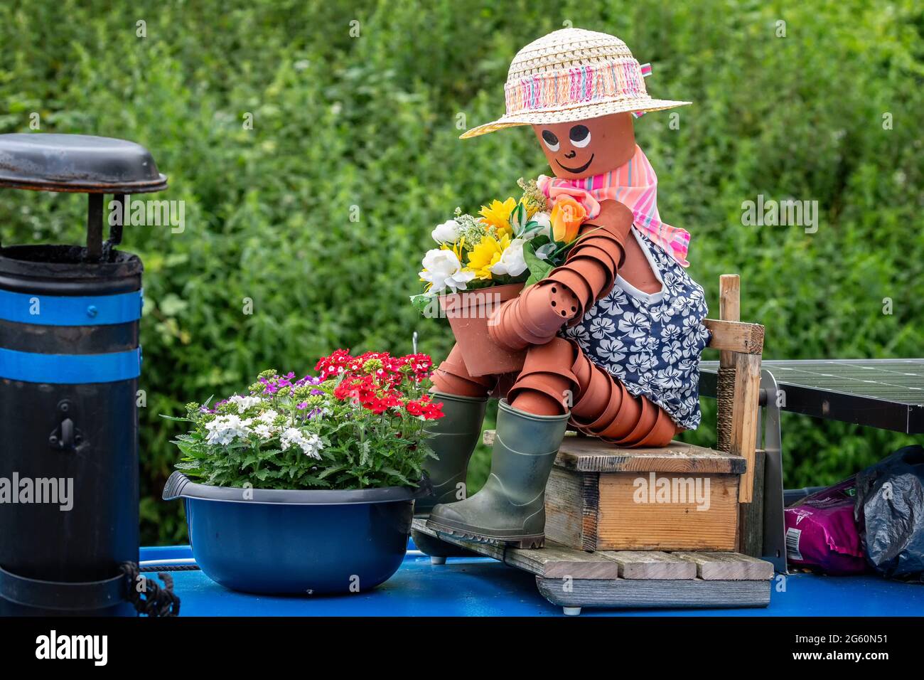 Nahaufnahme einer Frau aus Blumentöpfen, die auf einem Holzsitz sitzt und einen Blumentopf auf einem Kanalboot hält. Stockfoto