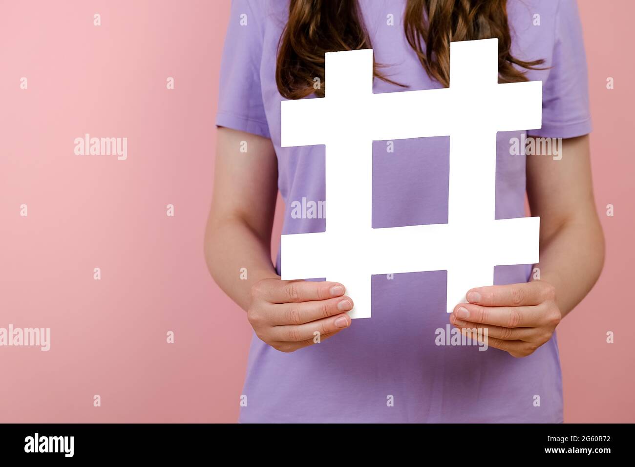 Nahaufnahme der jungen Frau hält große große große weiße Hashtag-Zeichen, Konzept der trendigen Social-Media-Beiträge und Blogging, virale Web-Inhalte, Internet-Werbung Stockfoto