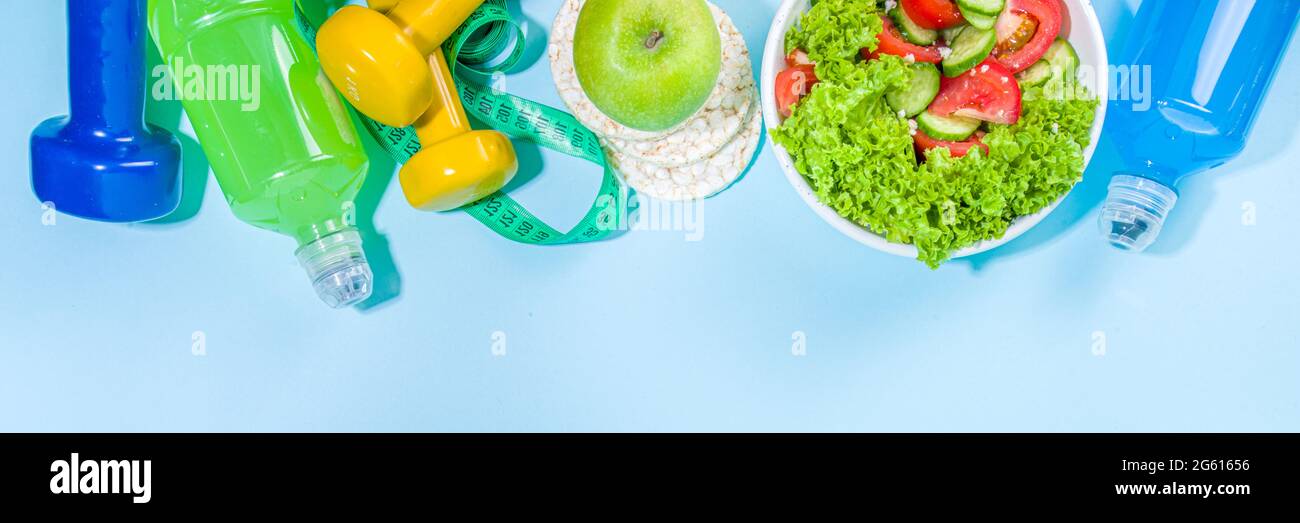 Sport gesunde Lebensweise, Diät-Konzept. Abnehmen Gewichtsverlust Fitness-Hintergrund mit Maßband, farbige Hanteln, Salat, Müsli knackig Brot, Spor Stockfoto