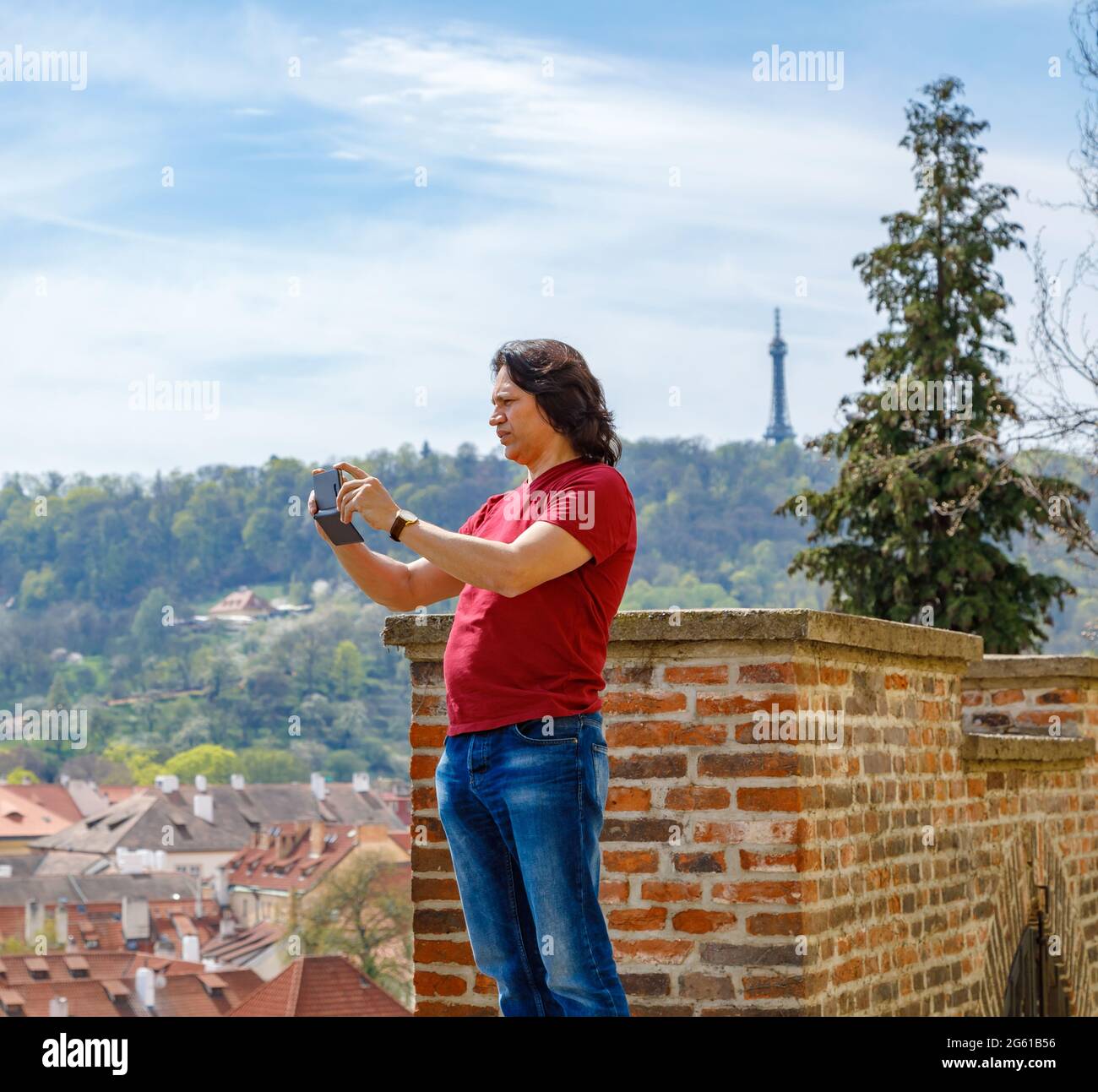 Ein Mann steht auf einer Backsteinmauer und fotografiert das Panorama von Prag. Reise Stockfoto