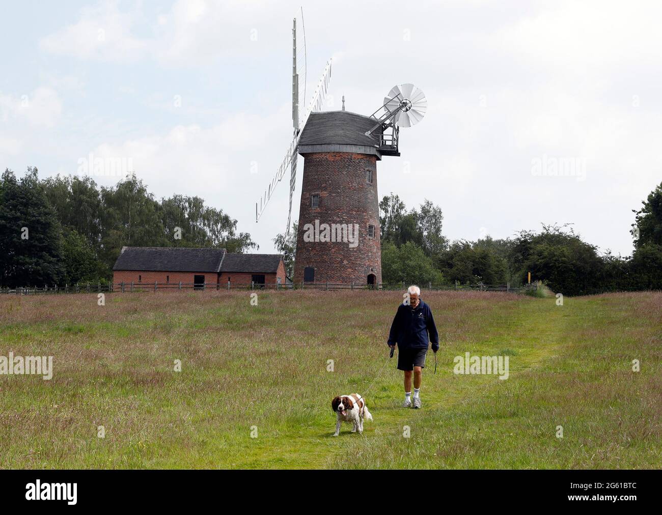 Swannington, Leicestershire, Großbritannien. Juli 2021. Ein Mann geht mit seinem Hund an Hough Mill vorbei. Swannington ist ein ehemaliges Bergbaudorf zwischen Coalville Stockfoto