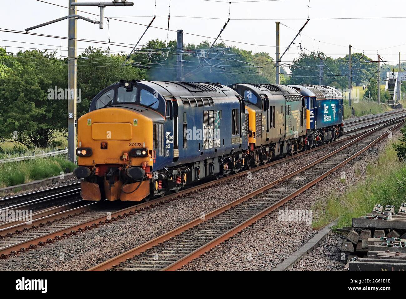 Drei der DRS, Direct Rail Services, Lokomotiven, 37423, 37038 und 57002, Fahren Sie auf der West Coast Main Line in Richtung Norden an der Balshaw Lane in Lancashire. Stockfoto