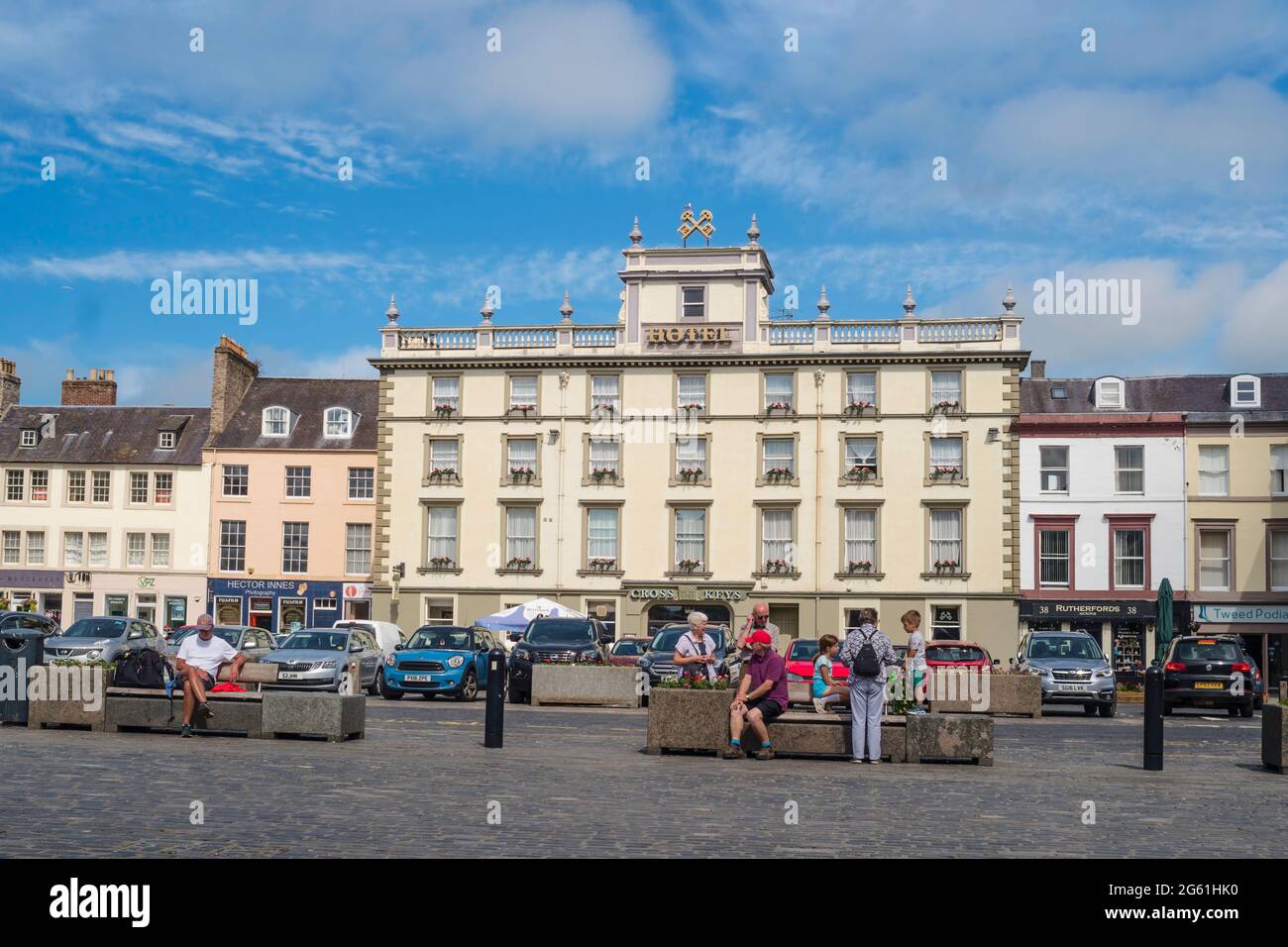Menschen sitzen auf dem Square in Kelso mit dem Cross Keys Hotel im Hintergrund, Scottish Borders, Schottland, Großbritannien Stockfoto