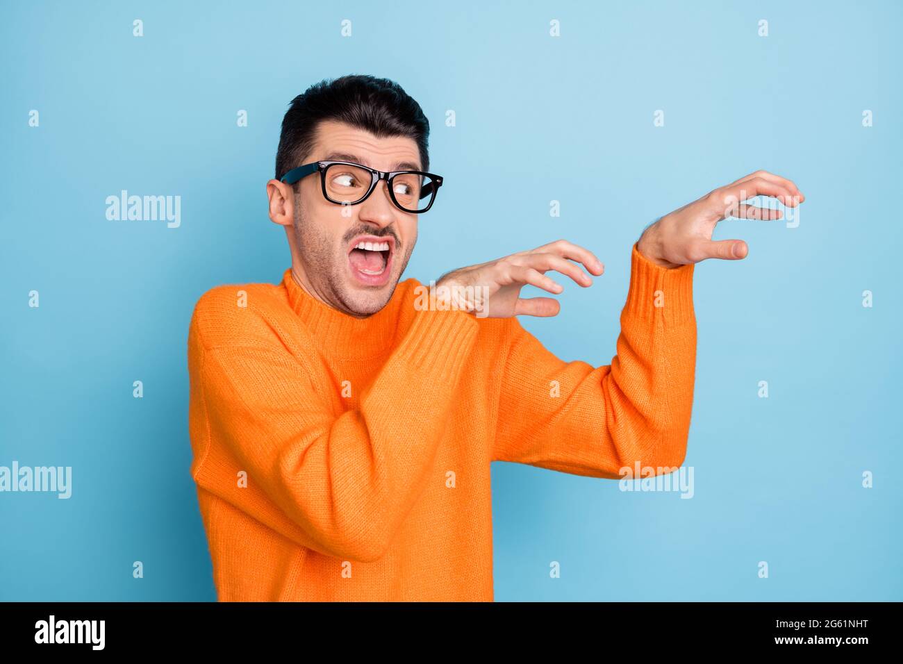 Foto von jungen Mann aggressive gruselig versuchen, beängstigend Sie suchen leeren Raum isoliert über blauen Hintergrund Stockfoto
